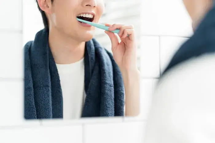鏡の前で歯を磨き、自分の歯並びをチェックする男性