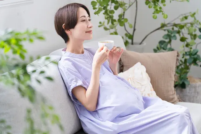 妊娠中にリラックスしながら飲み物を飲む妊婦